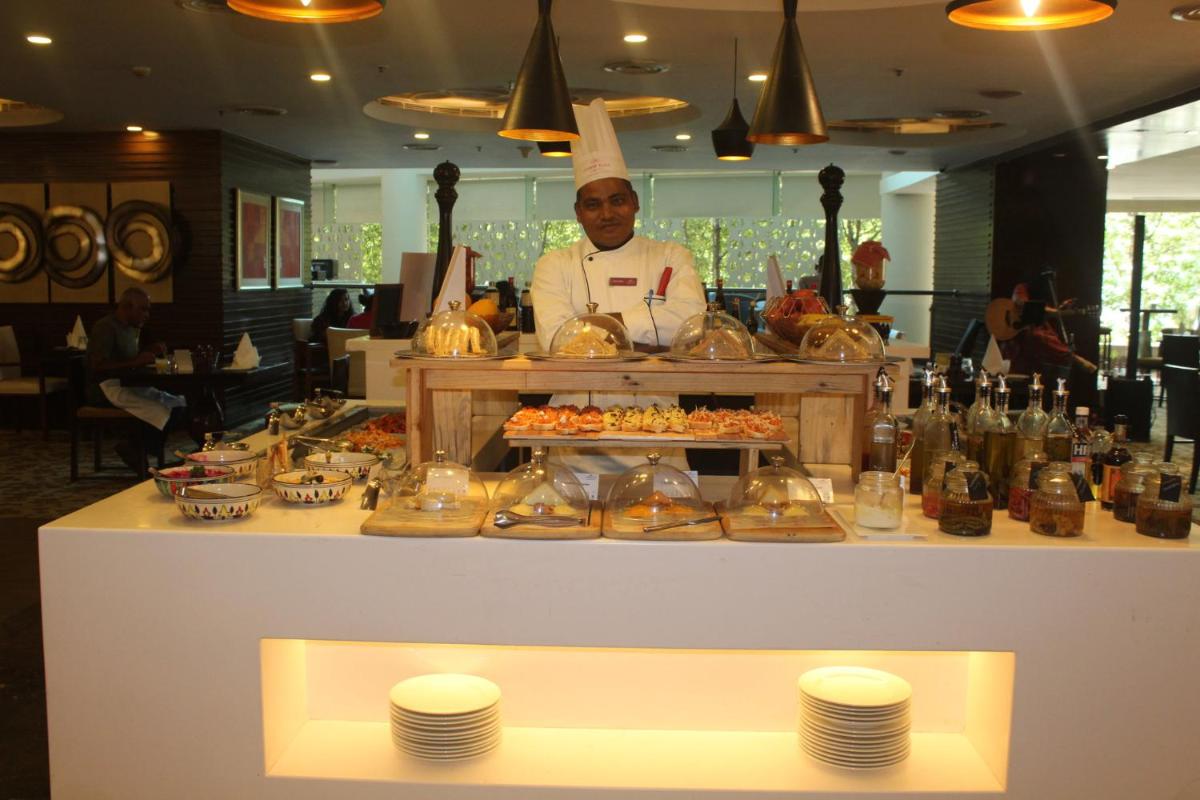 a man standing behind a counter with a buffet of food at Crowne Plaza Ahmedabad City Centre by IHG in Ahmedabad