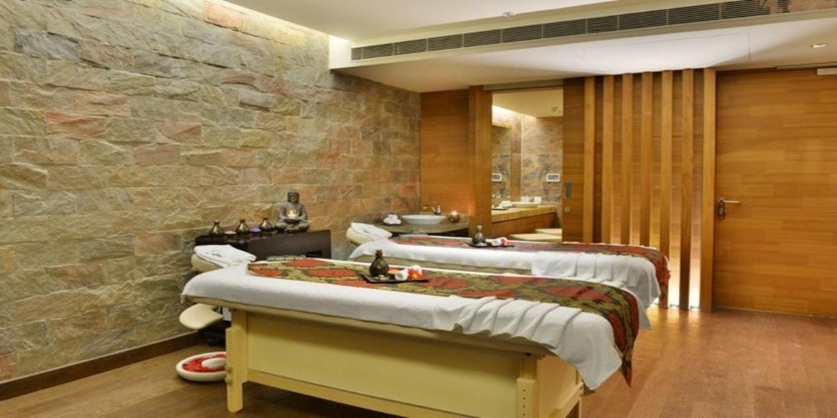 a room with three beds and a stone wall at Crowne Plaza Ahmedabad City Centre by IHG in Ahmedabad