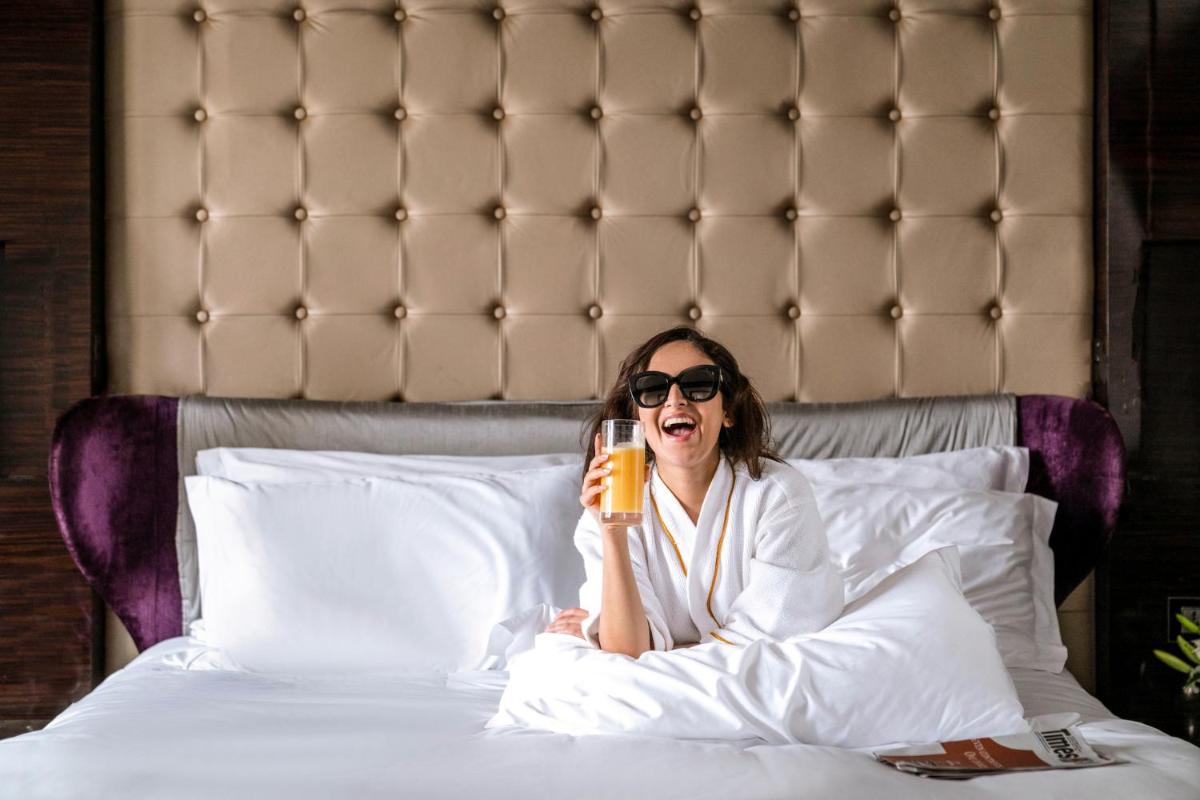 a woman sitting on a bed talking on a cell phone at Sofitel Mumbai BKC in Mumbai