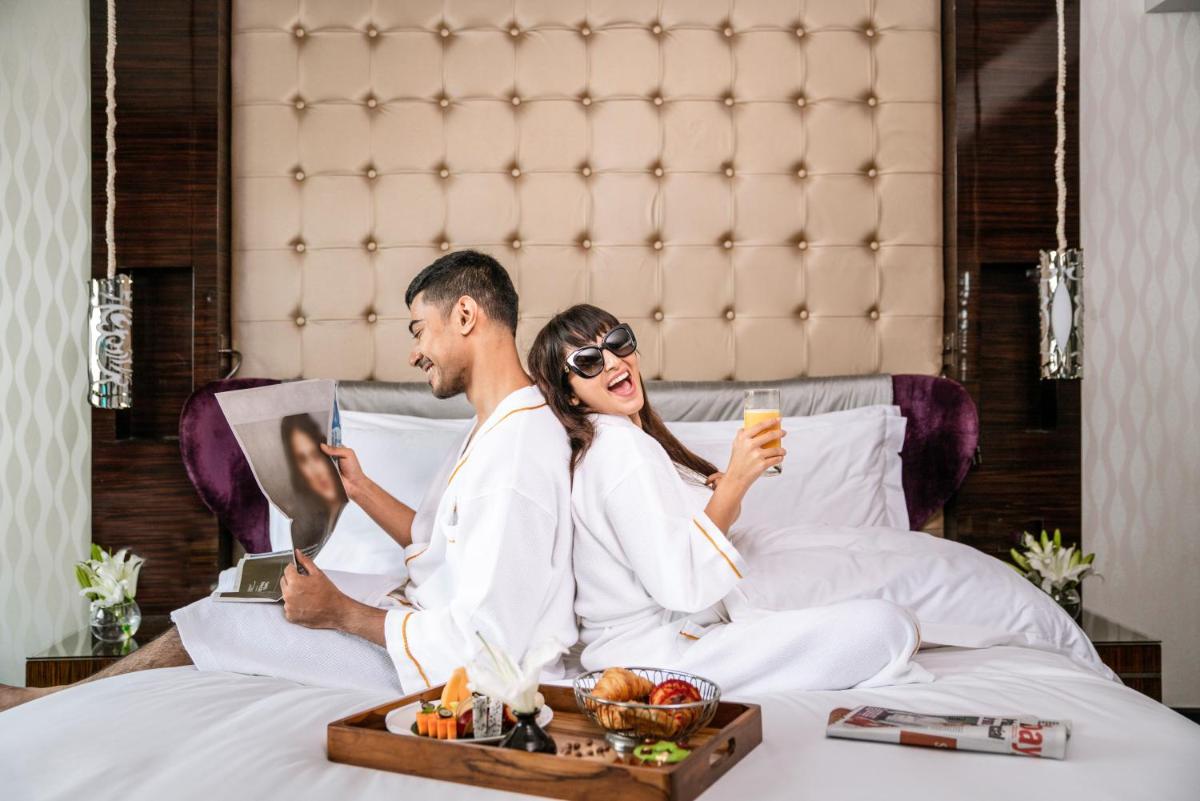 a man and woman sitting in bed with a tray of food at Sofitel Mumbai BKC in Mumbai