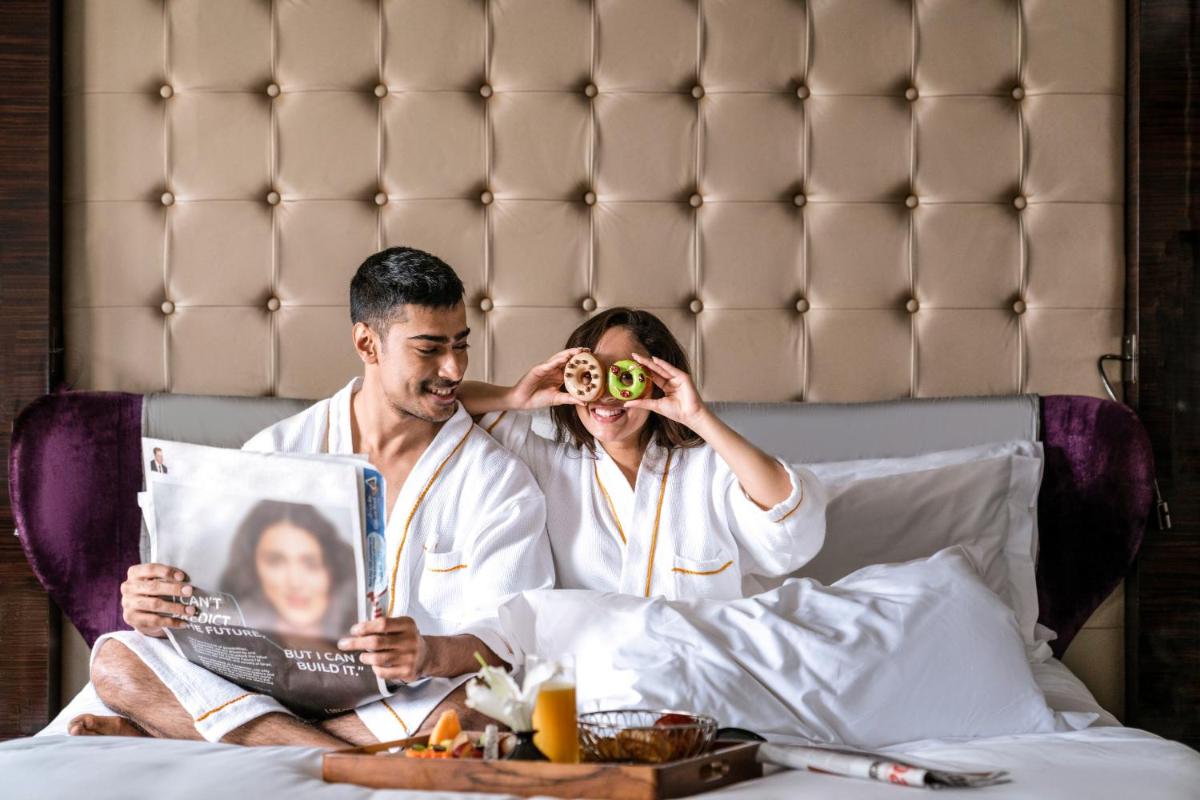 two men sitting in bed looking at a magazine at Sofitel Mumbai BKC in Mumbai