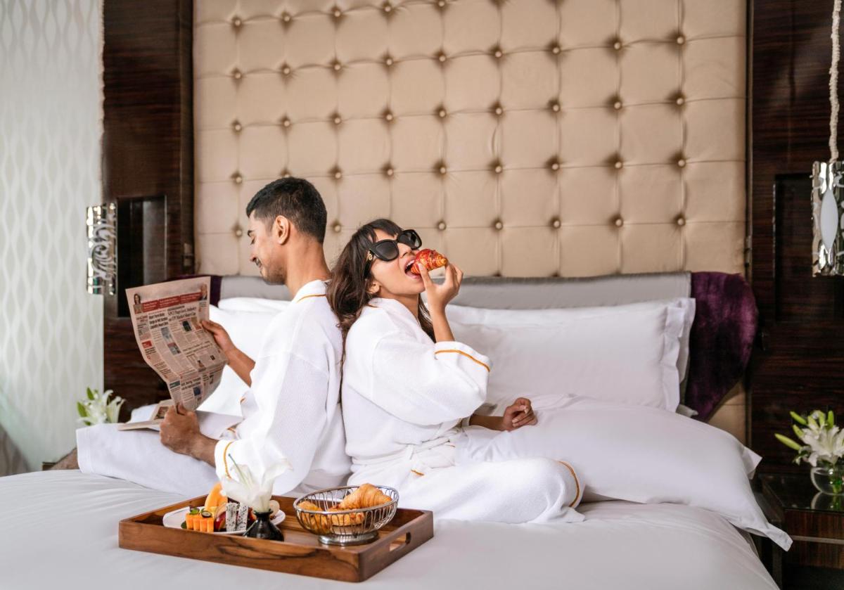 a man and a woman sitting on a bed eating food at Sofitel Mumbai BKC in Mumbai