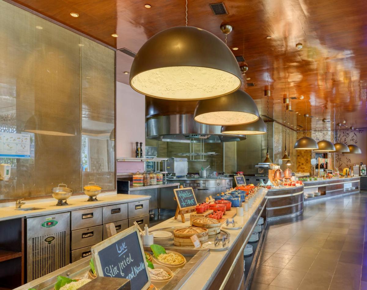 a large kitchen with a long counter with food at Novotel Bengaluru Outer Ring Road in Bengaluru