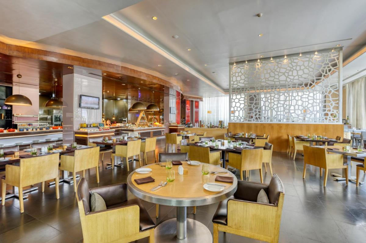 a dining room with tables and chairs and a restaurant at Novotel Bengaluru Outer Ring Road in Bengaluru