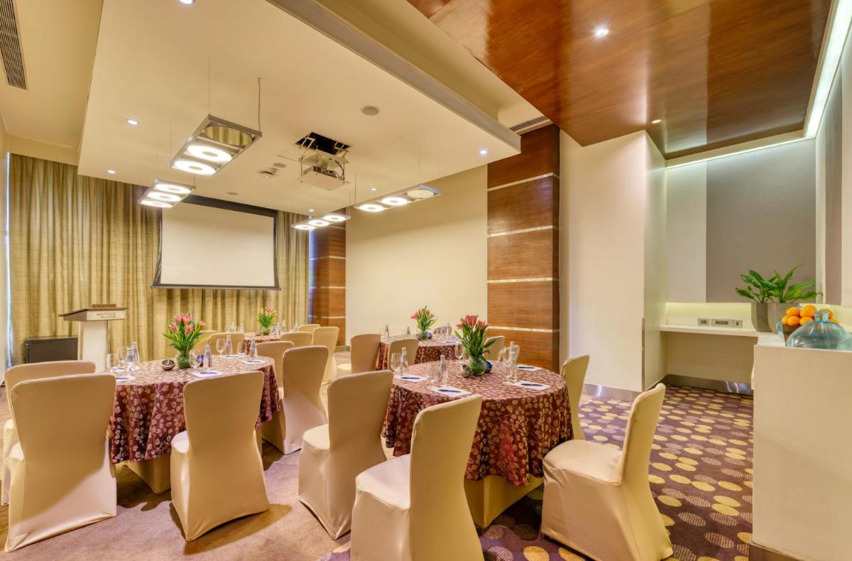 a conference room with tables and chairs and a podium at Novotel Bengaluru Outer Ring Road in Bengaluru