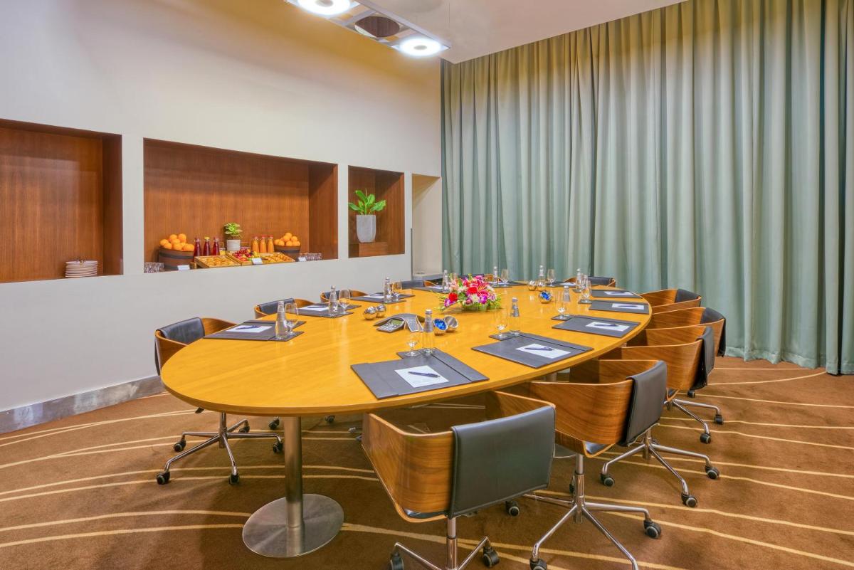 a conference room with a large wooden table and chairs at Novotel Bengaluru Outer Ring Road in Bengaluru