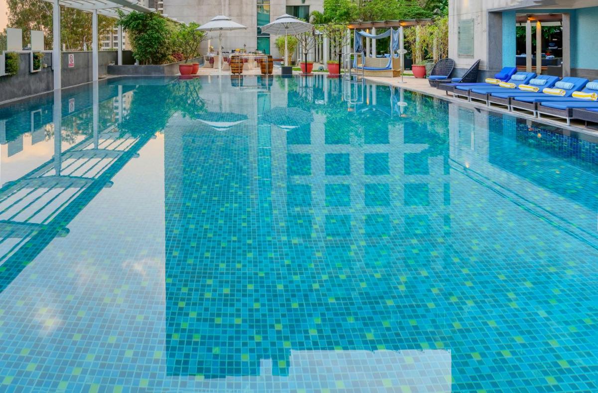a swimming pool with blue tiles in a building at Novotel Bengaluru Outer Ring Road in Bengaluru