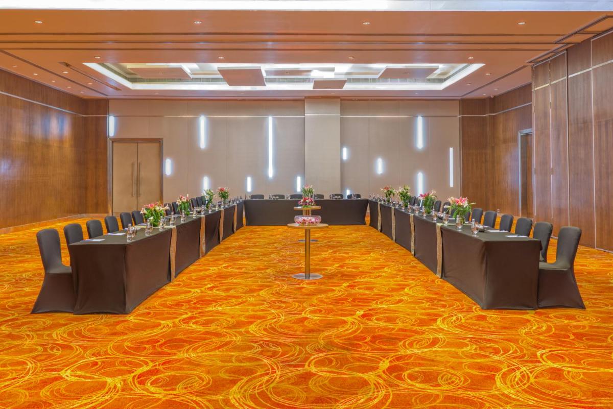 a conference room with a row of tables and chairs at Novotel Bengaluru Outer Ring Road in Bengaluru