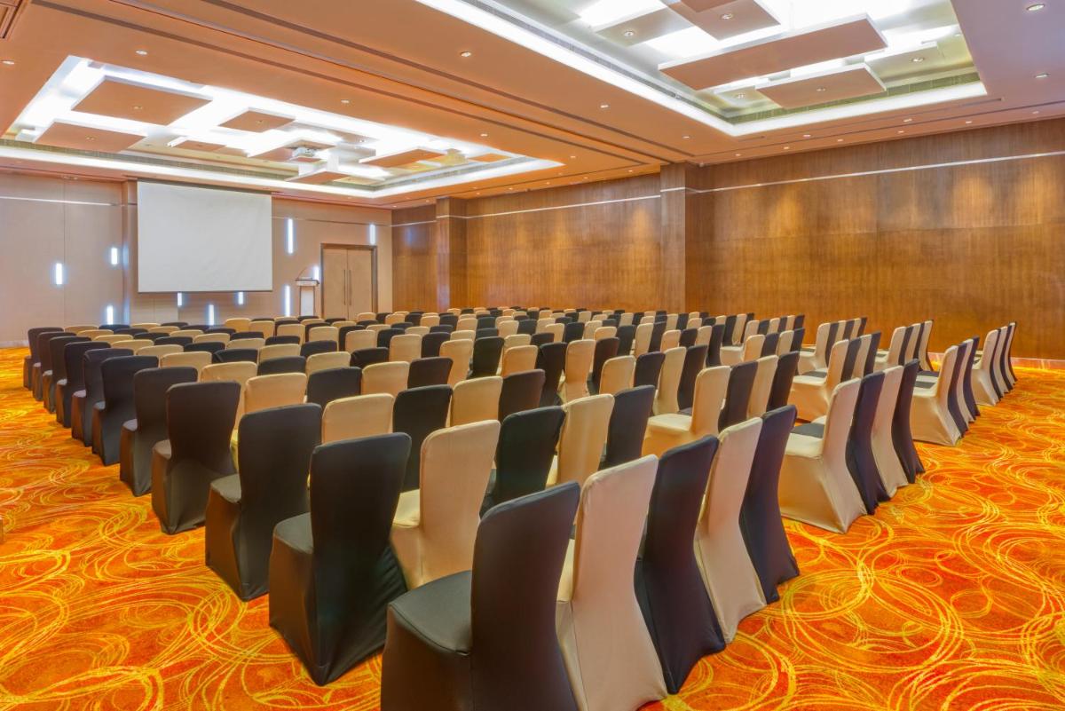 a conference room with chairs and a projection screen at Novotel Bengaluru Outer Ring Road in Bengaluru