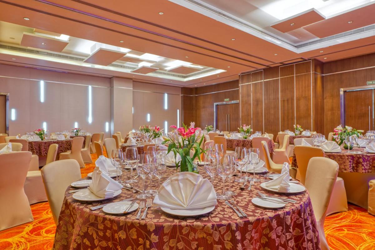 a large banquet room with tables and chairs and flowers at Novotel Bengaluru Outer Ring Road in Bengaluru