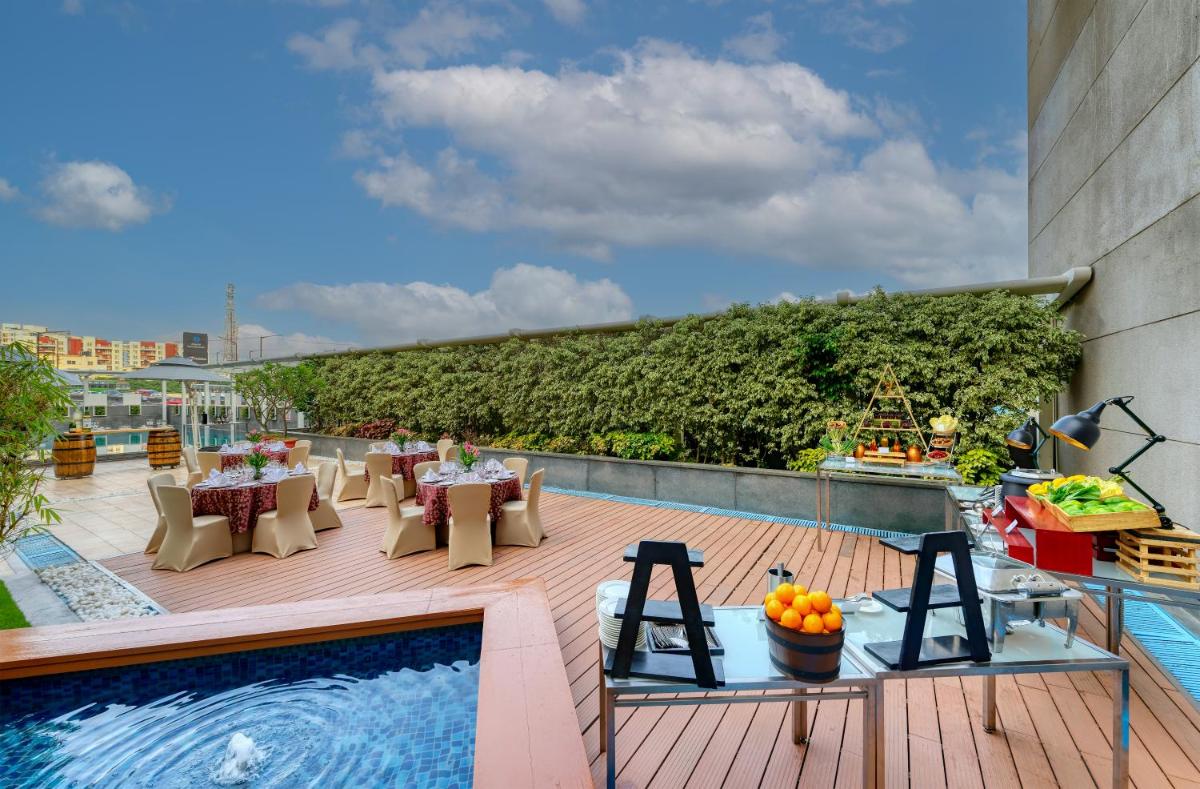 a rooftop deck with tables and a swimming pool at Novotel Bengaluru Outer Ring Road in Bengaluru