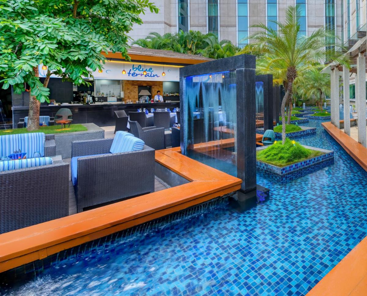 a resort with a pool with chairs and a bar at Novotel Bengaluru Outer Ring Road in Bengaluru