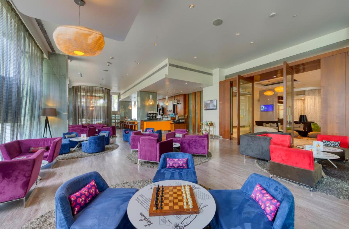 a hotel lobby with purple chairs and tables at Novotel Bengaluru Outer Ring Road in Bengaluru
