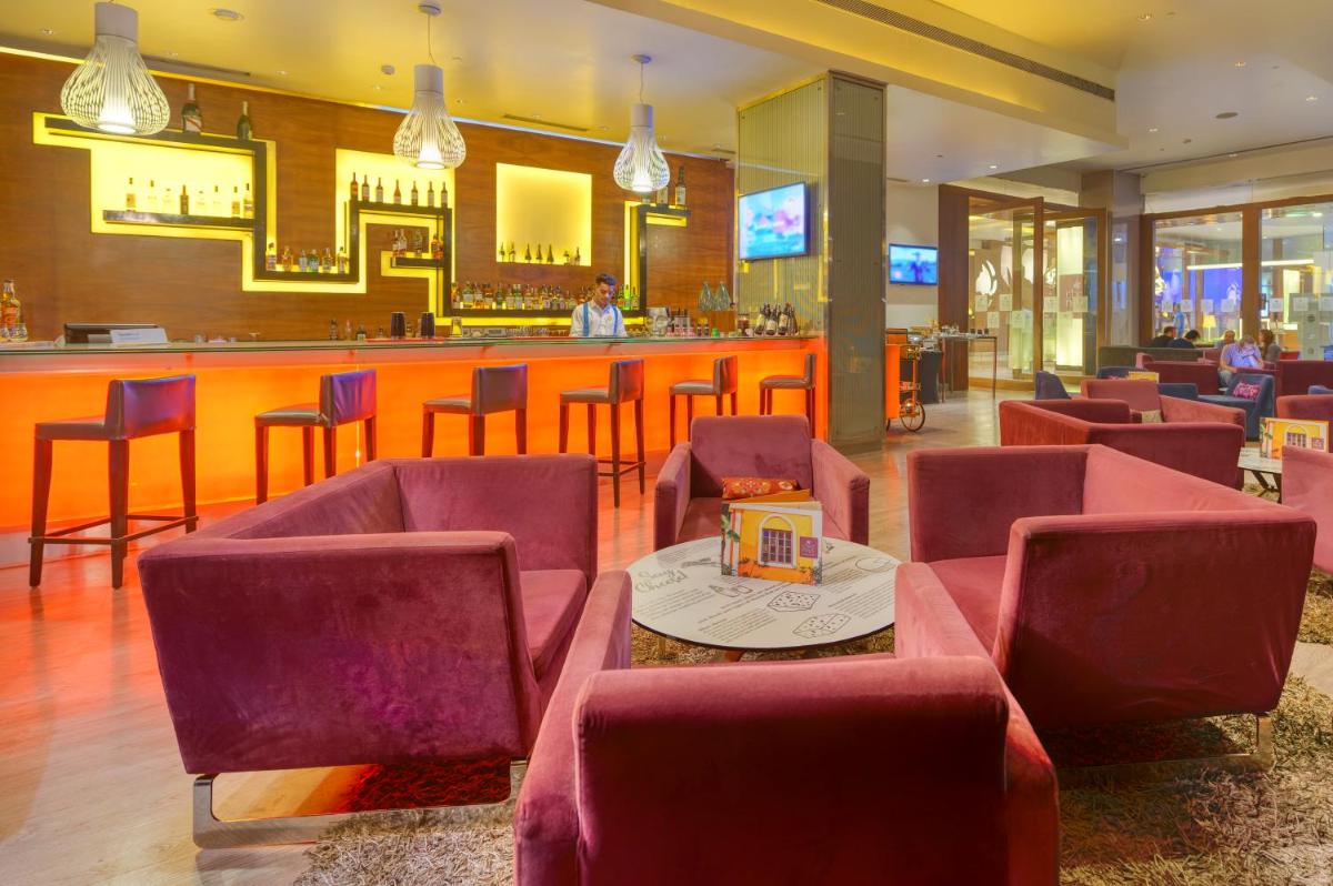 a restaurant with red chairs and a bar at Novotel Bengaluru Outer Ring Road in Bengaluru
