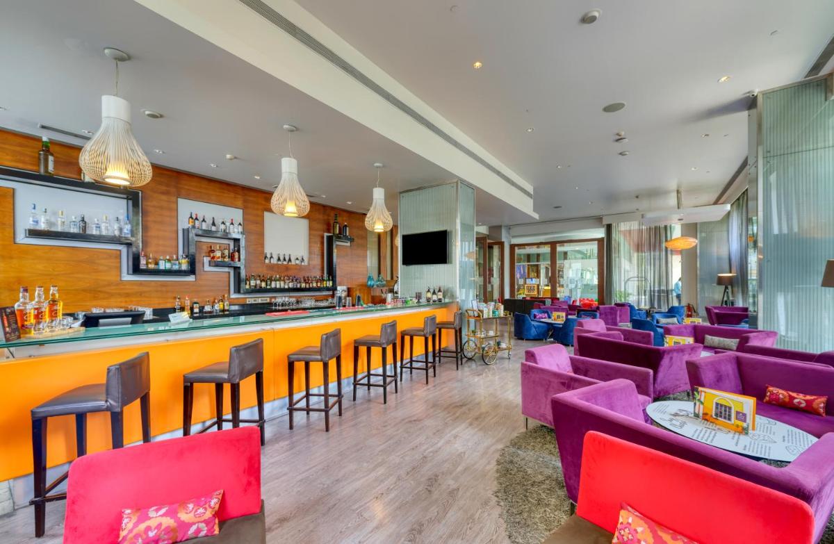 a restaurant with purple chairs and a bar at Novotel Bengaluru Outer Ring Road in Bengaluru