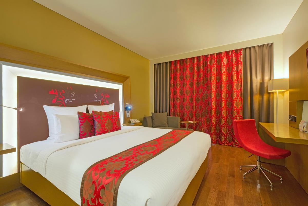 a hotel room with a large bed and a red chair at Novotel Bengaluru Outer Ring Road in Bengaluru