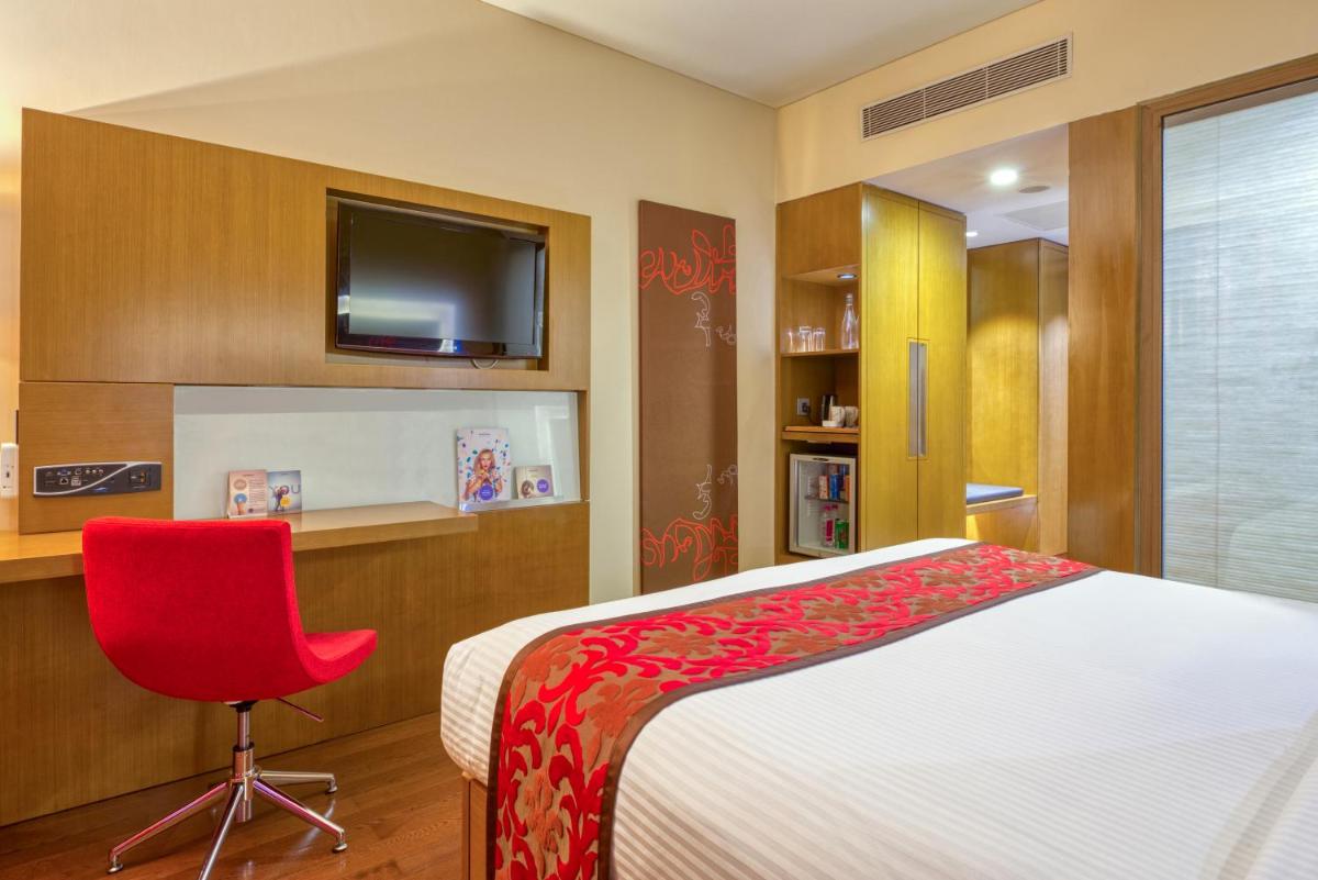 a bedroom with a bed and a red chair at Novotel Bengaluru Outer Ring Road in Bengaluru