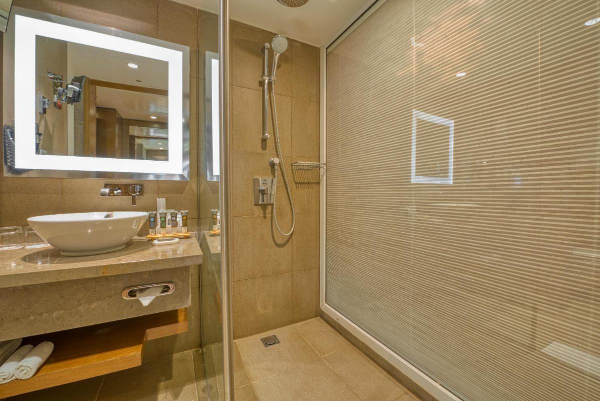 a bathroom with a glass shower and a sink at Novotel Bengaluru Outer Ring Road in Bengaluru