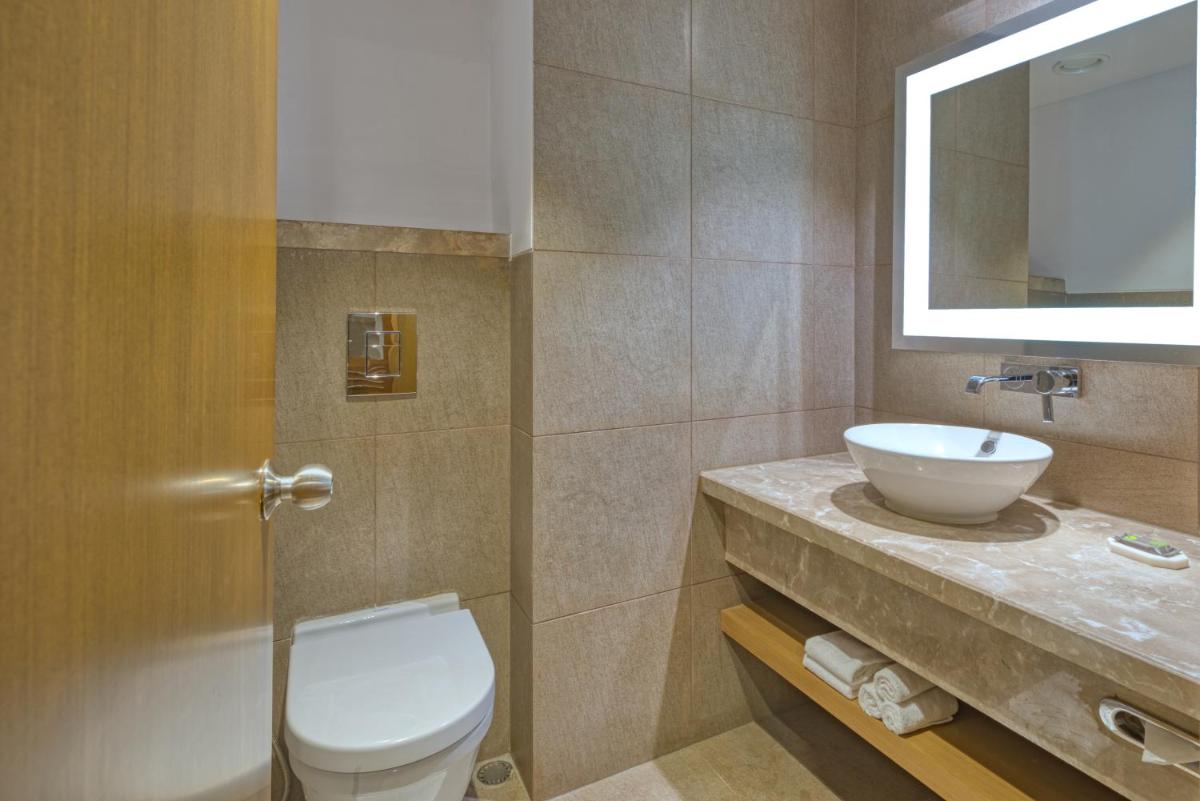 a bathroom with a toilet and a sink at Novotel Bengaluru Outer Ring Road in Bengaluru
