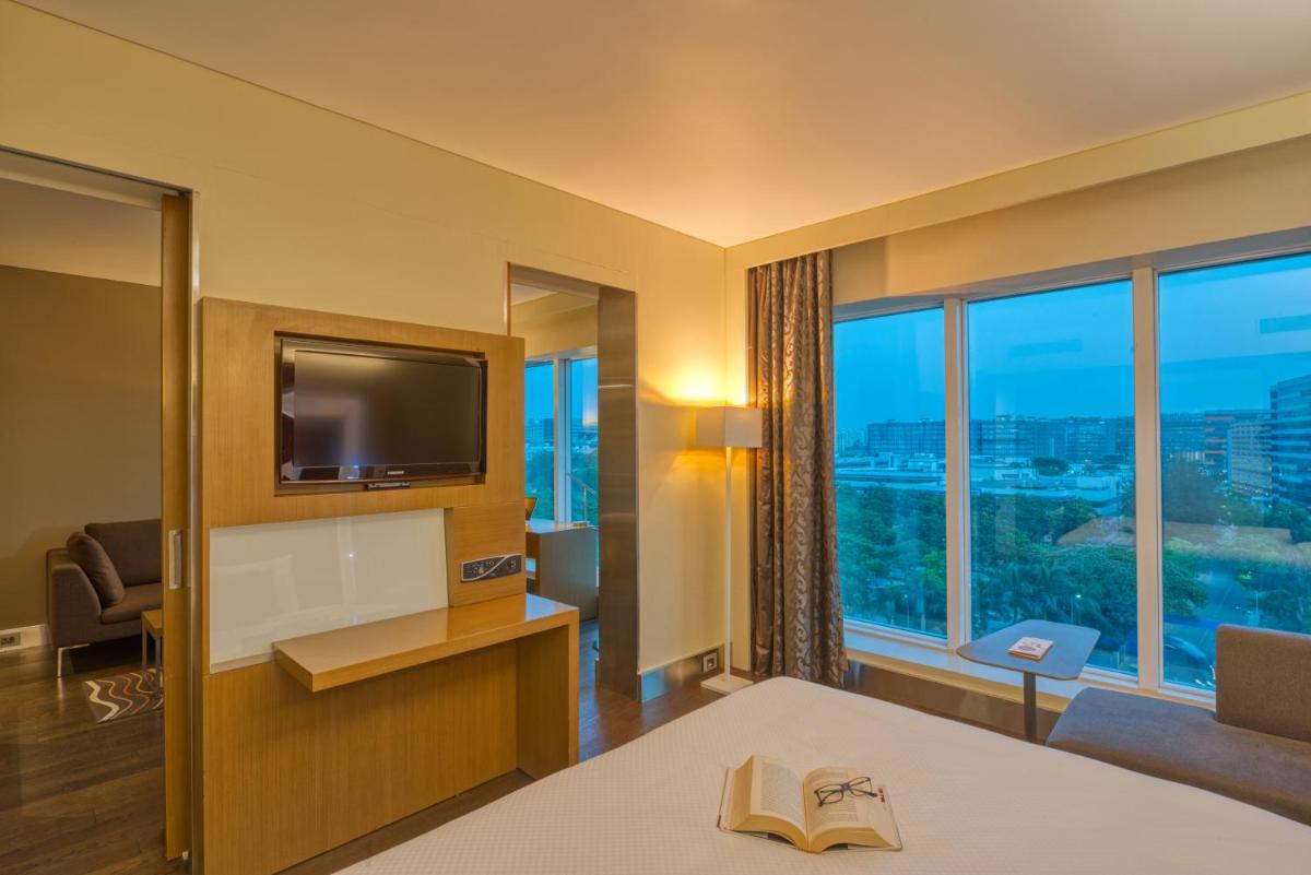 a hotel room with a bed and a tv at Novotel Bengaluru Outer Ring Road in Bengaluru