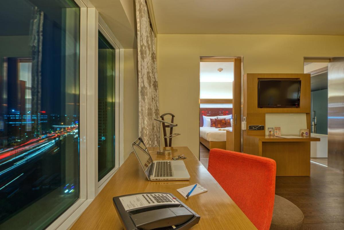 a hotel room with a desk with a laptop on it at Novotel Bengaluru Outer Ring Road in Bengaluru