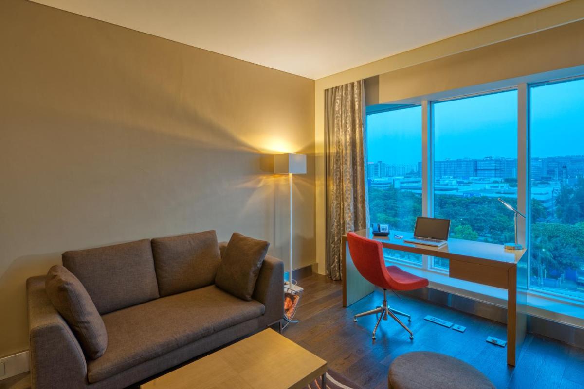 a living room with a couch and a desk with a computer at Novotel Bengaluru Outer Ring Road in Bengaluru