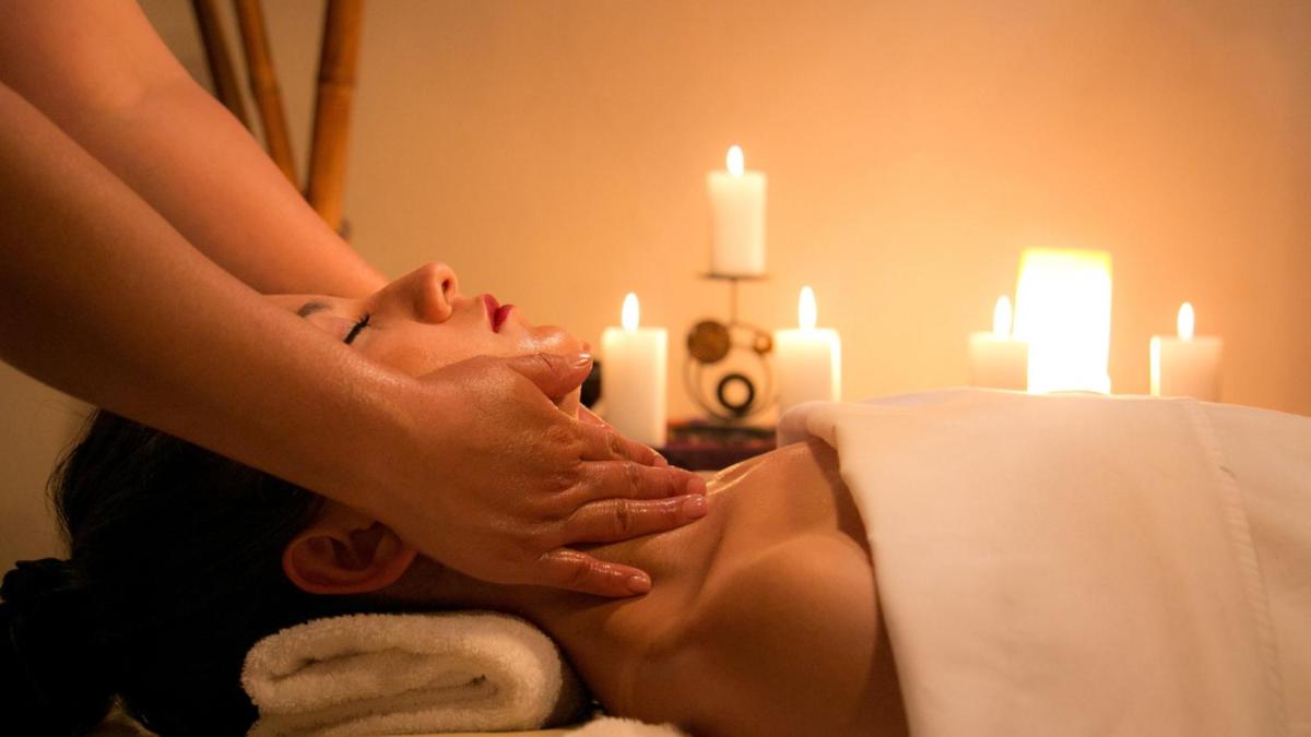 a woman getting a massage in front of candles at Novotel Bengaluru Outer Ring Road in Bengaluru