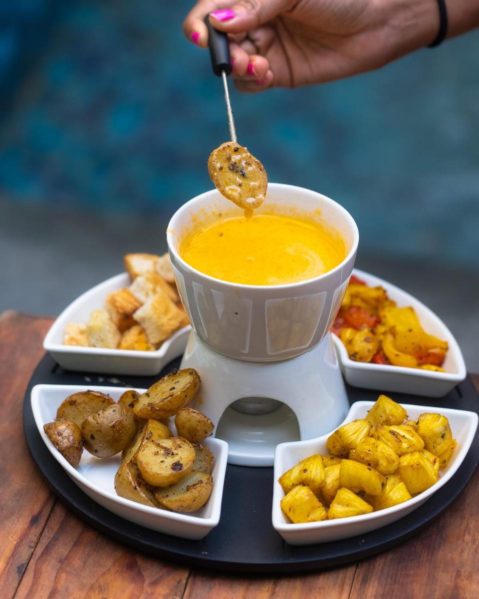 a person dipping a spoon into a bowl of soup at Novotel Bengaluru Outer Ring Road in Bengaluru