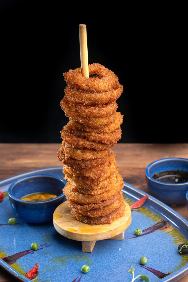 a stack of food on a wooden stick on a table at Novotel Bengaluru Outer Ring Road in Bengaluru