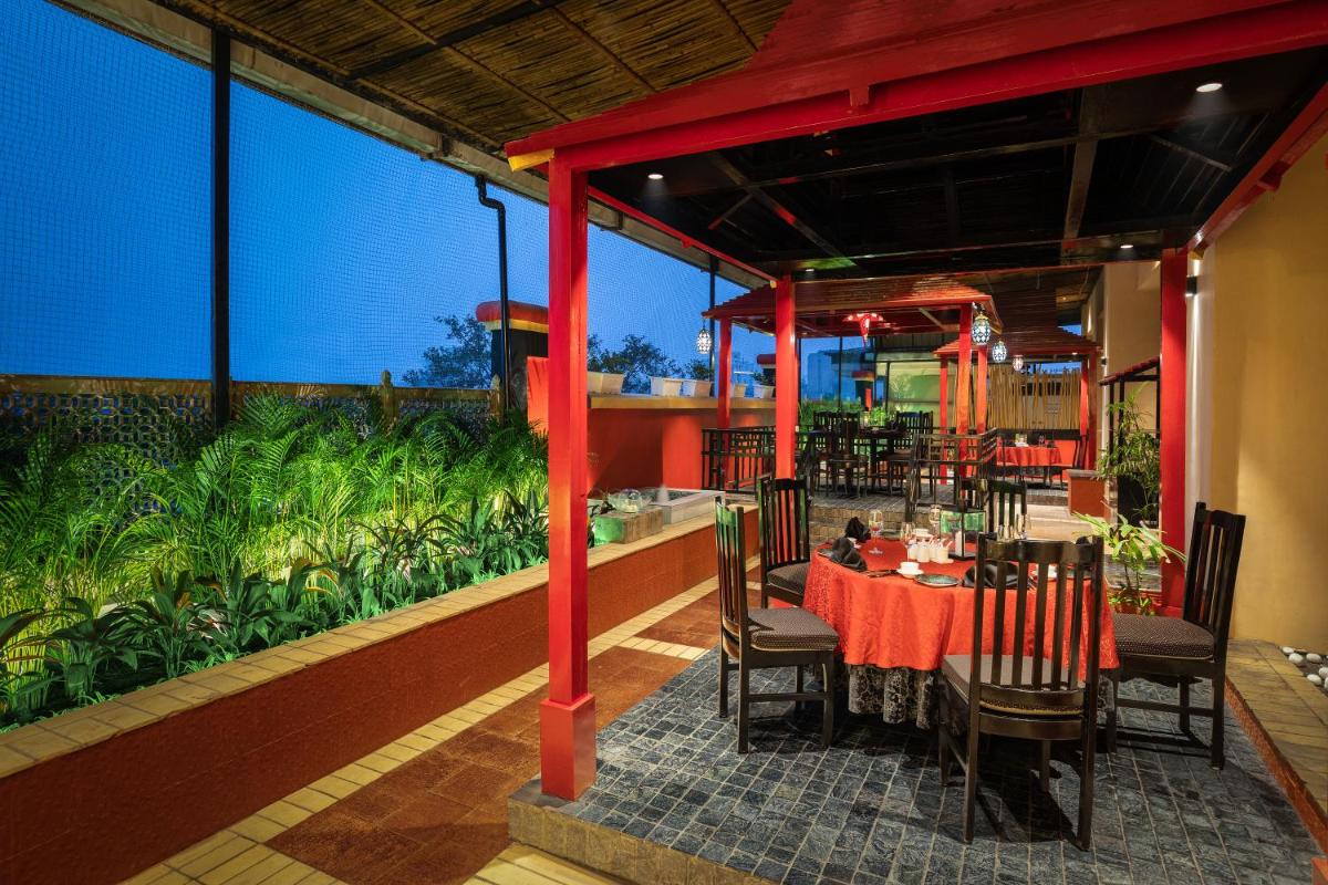 a restaurant with a table and chairs in a room with plants at Radisson Jaipur City Center in Jaipur