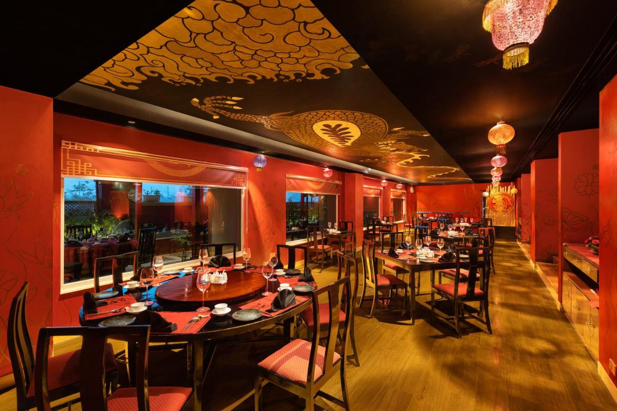a restaurant with red walls and tables and chairs at Radisson Jaipur City Center in Jaipur