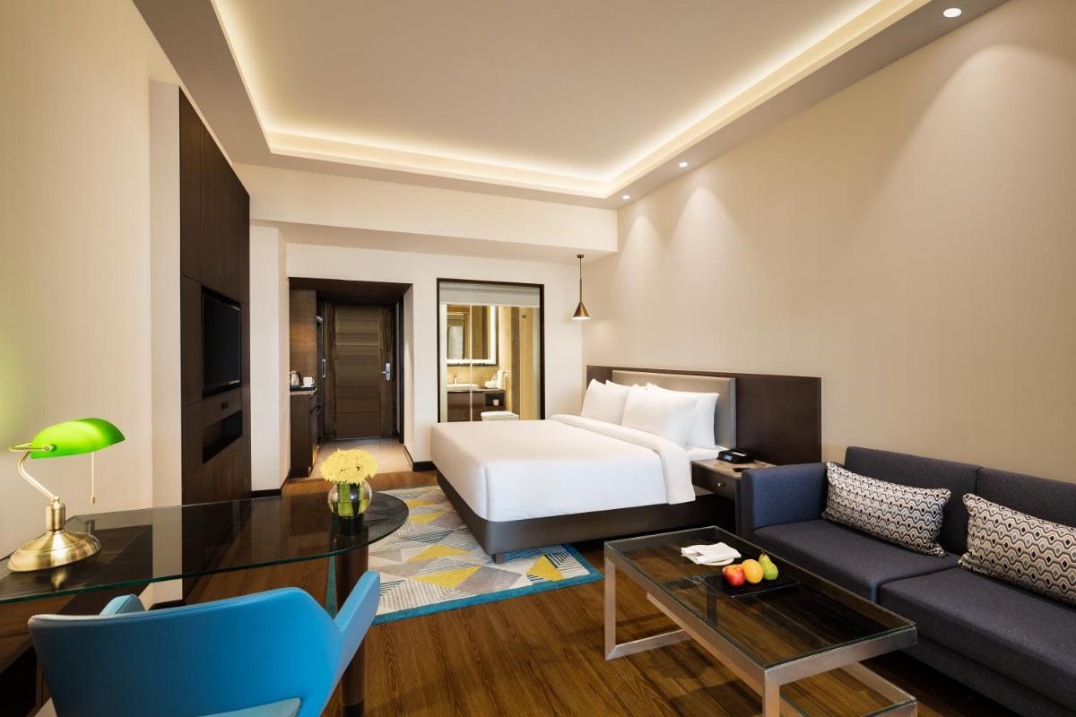 a hotel room with a bed and a couch at Radisson Jaipur City Center in Jaipur