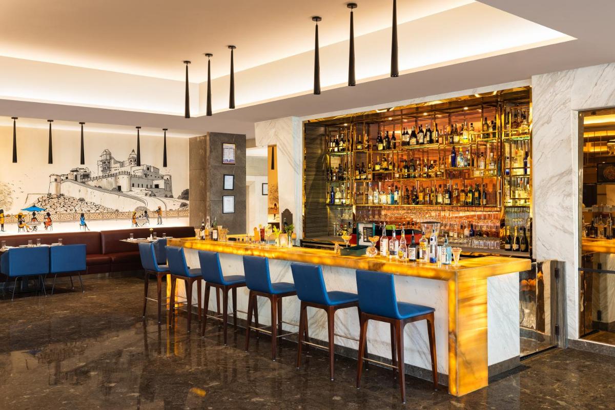 a bar in a restaurant with blue bar stools at Radisson Jaipur City Center in Jaipur