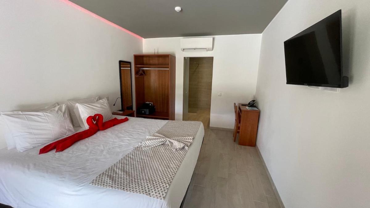 um quarto com uma cama branca com uma fita vermelha em Villa 3 Caparica - Lisbon Gay Beach Resort em Charneca