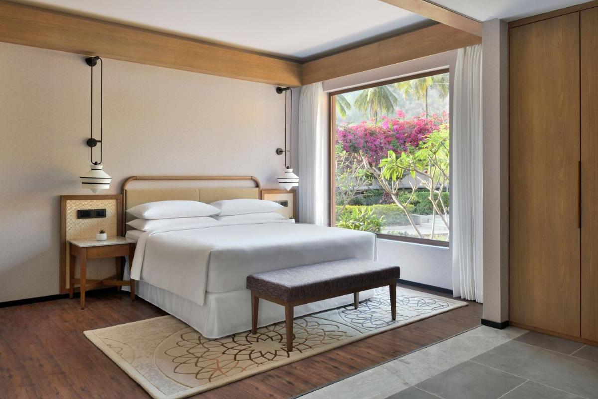 a bedroom with a bed and a large window at Mulberry Shades Bengaluru Nandi Hills - a Tribute Portfolio Resort in Bengaluru a bedroom with a bed and a large window at Mulberry Shades Bengaluru Nandi Hills - a Tribute Portfolio Resort in Bengaluru