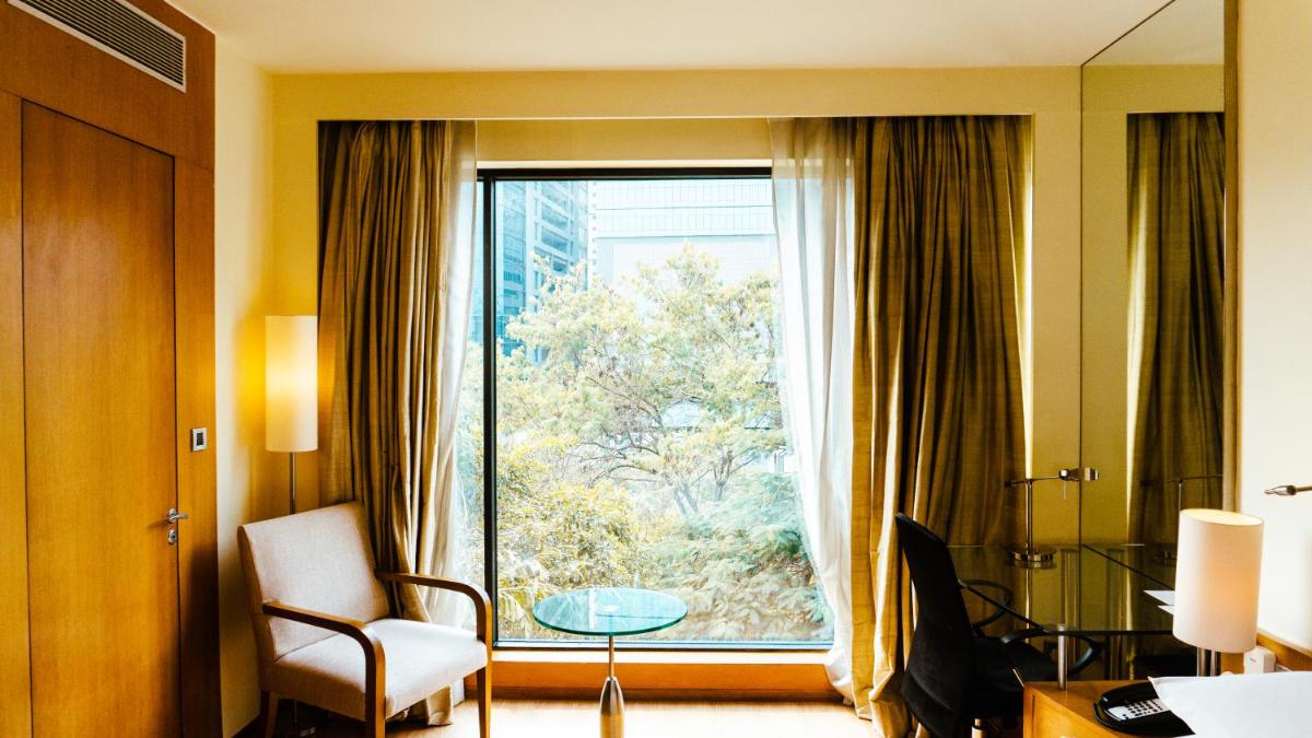 a room with a large window with a chair and a table at Hyatt Hyderabad Gachibowli in Hyderabad