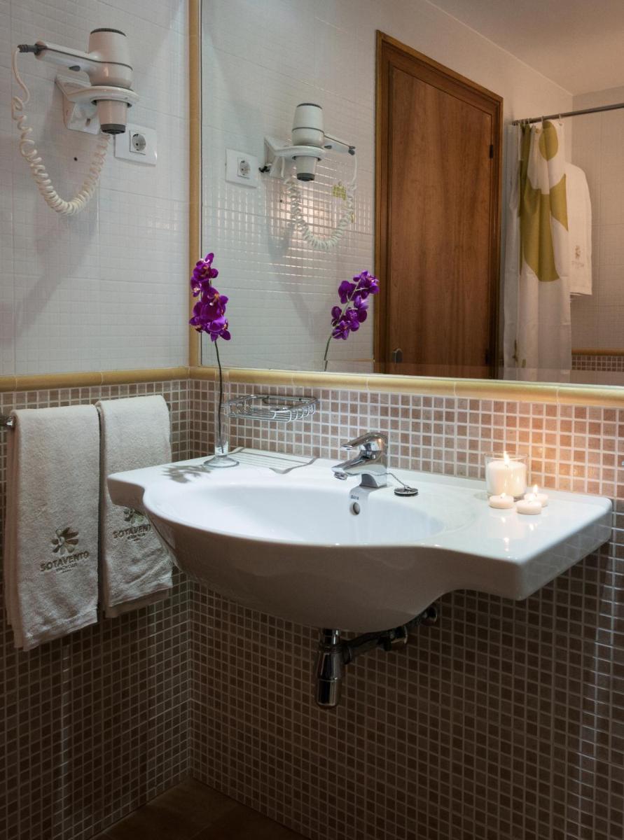 Un baño con un lavabo blanco y un espejo. en Sotavento Beach Club, en Costa Calma