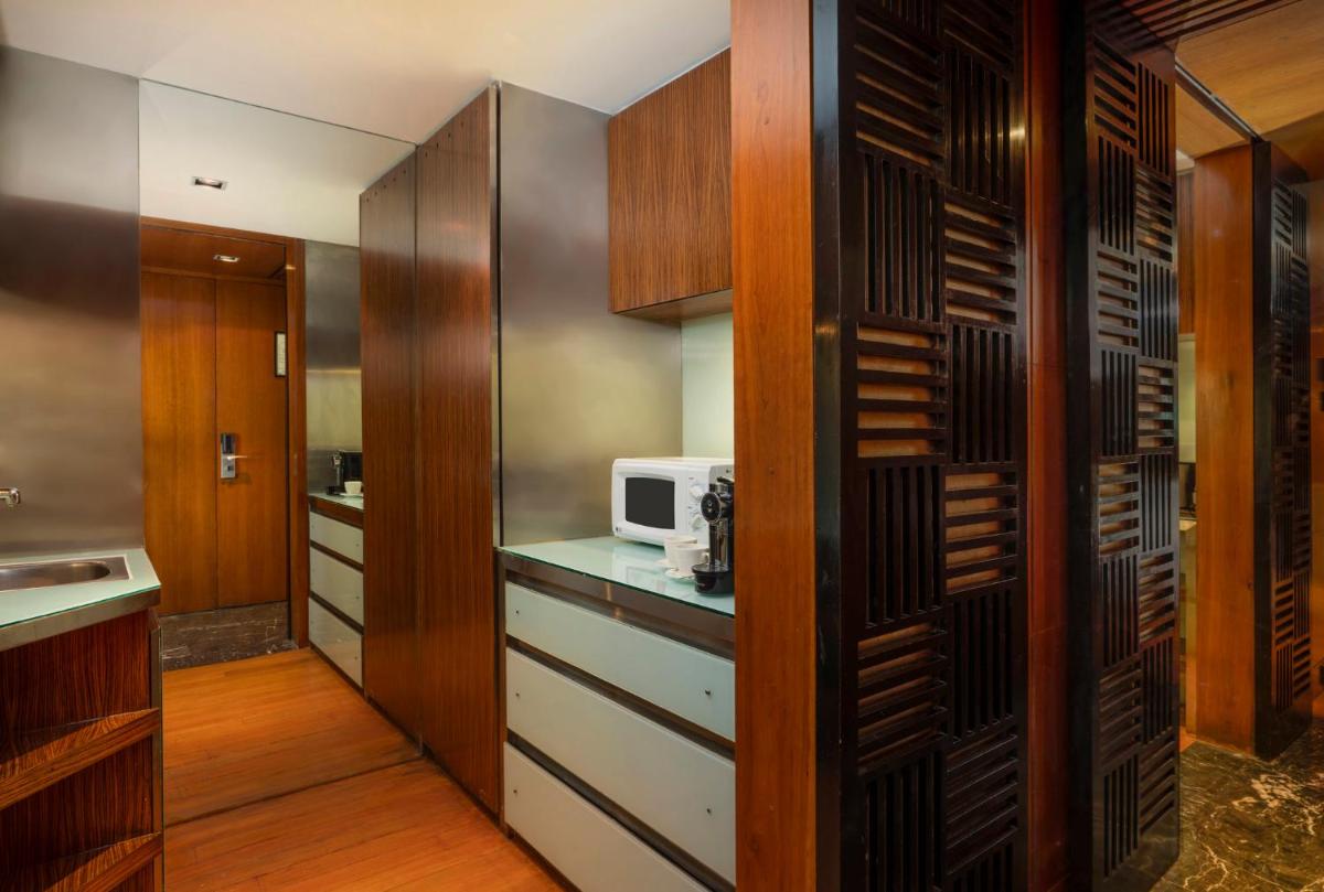 a kitchen with wooden cabinets and a microwave at InterContinental Marine Drive Mumbai by IHG in Mumbai