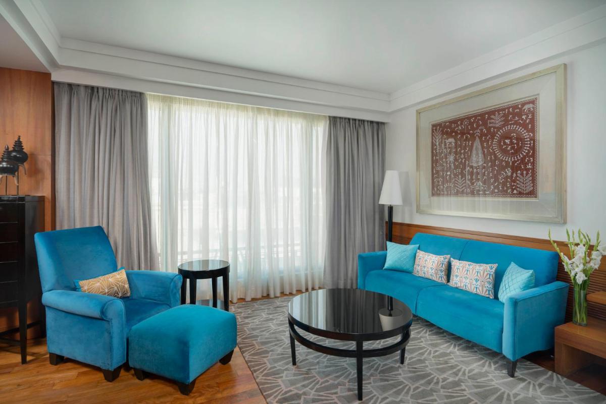 a living room with a blue couch and chairs at InterContinental Marine Drive Mumbai by IHG in Mumbai