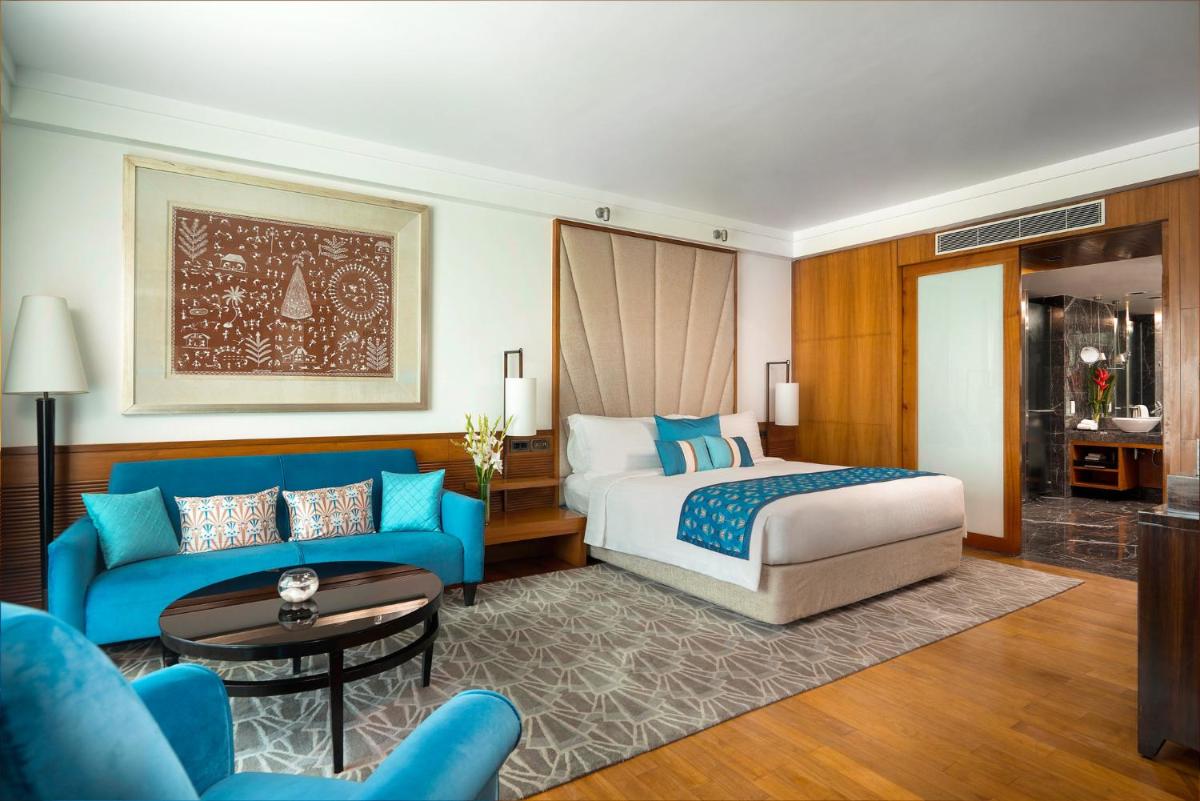 a hotel room with a bed and a blue couch at InterContinental Marine Drive Mumbai by IHG in Mumbai