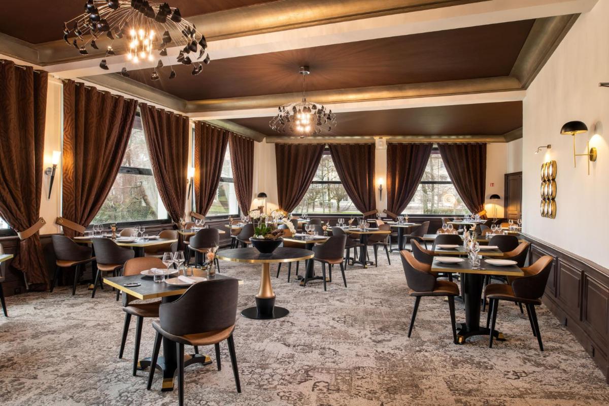 un restaurant avec des tables, des chaises et des fenêtres dans l'établissement Hôtel Beau Rivage, à Gérardmer