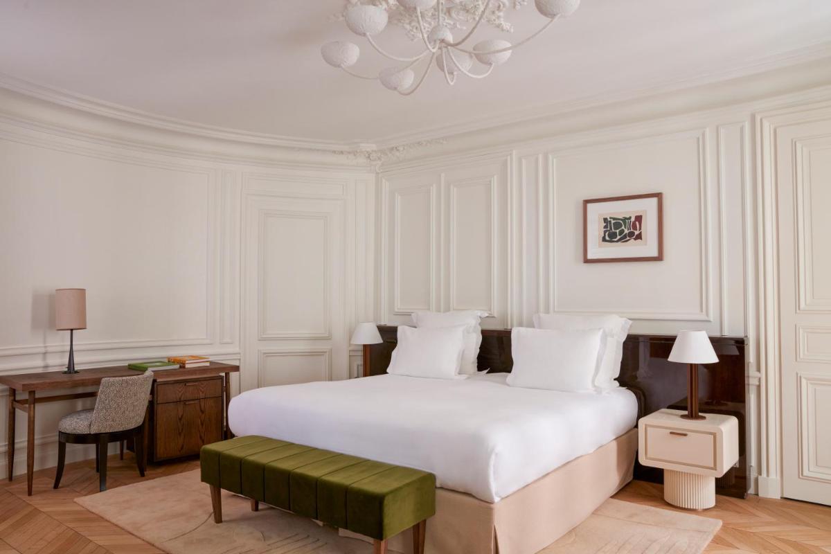 une chambre blanche avec un lit, un bureau et un lustre dans l'établissement Maison Delano Paris, à Paris