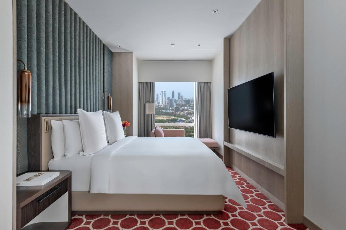 a hotel room with a bed and a flat screen tv at Four Seasons Hotel Mumbai in Mumbai
