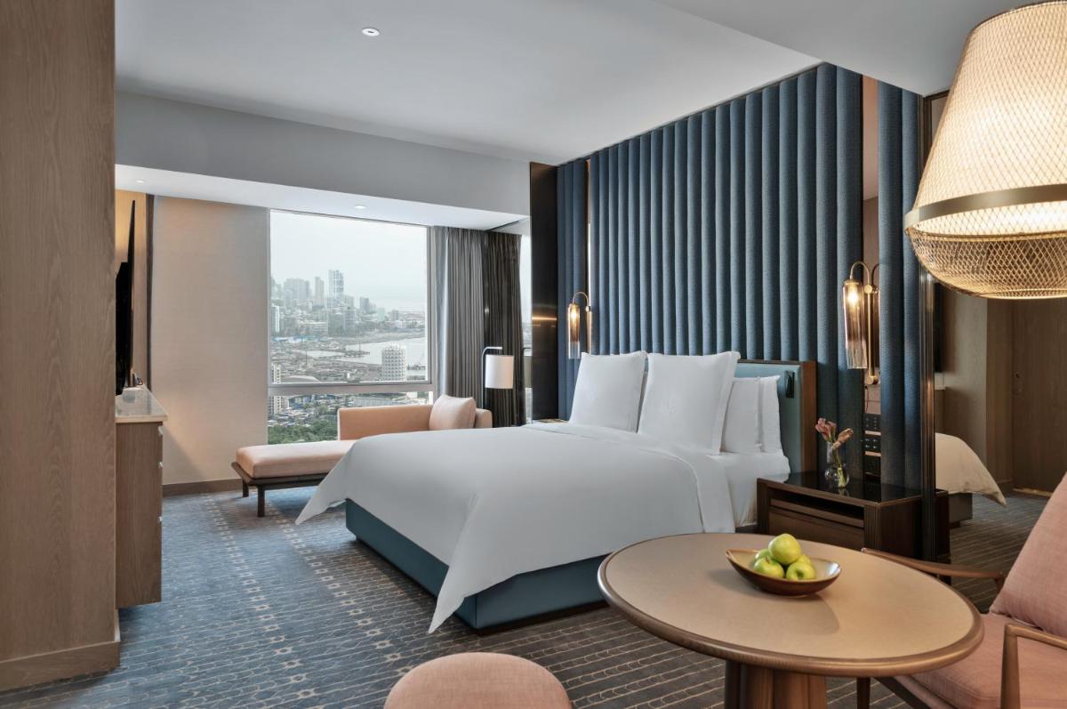 a hotel room with a bed and a large window at Four Seasons Hotel Mumbai in Mumbai