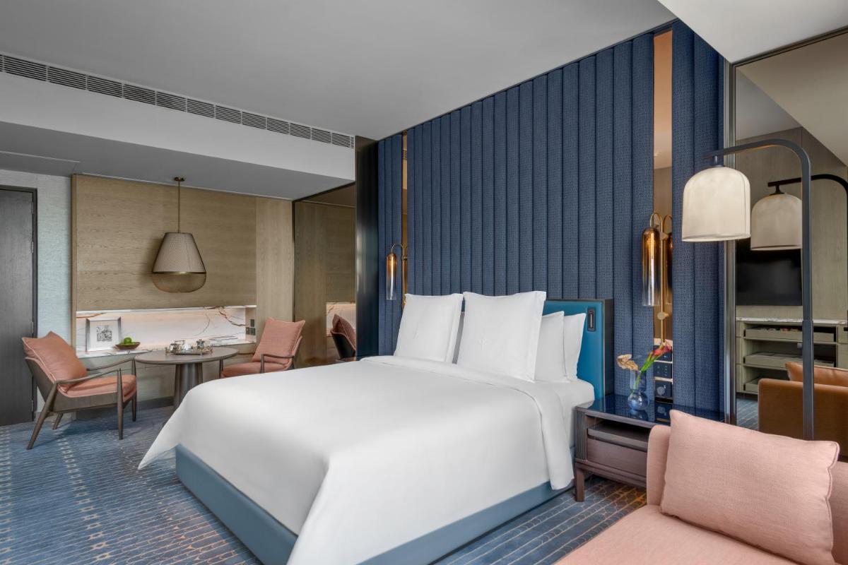 a bedroom with a large white bed and a dining room at Four Seasons Hotel Mumbai in Mumbai