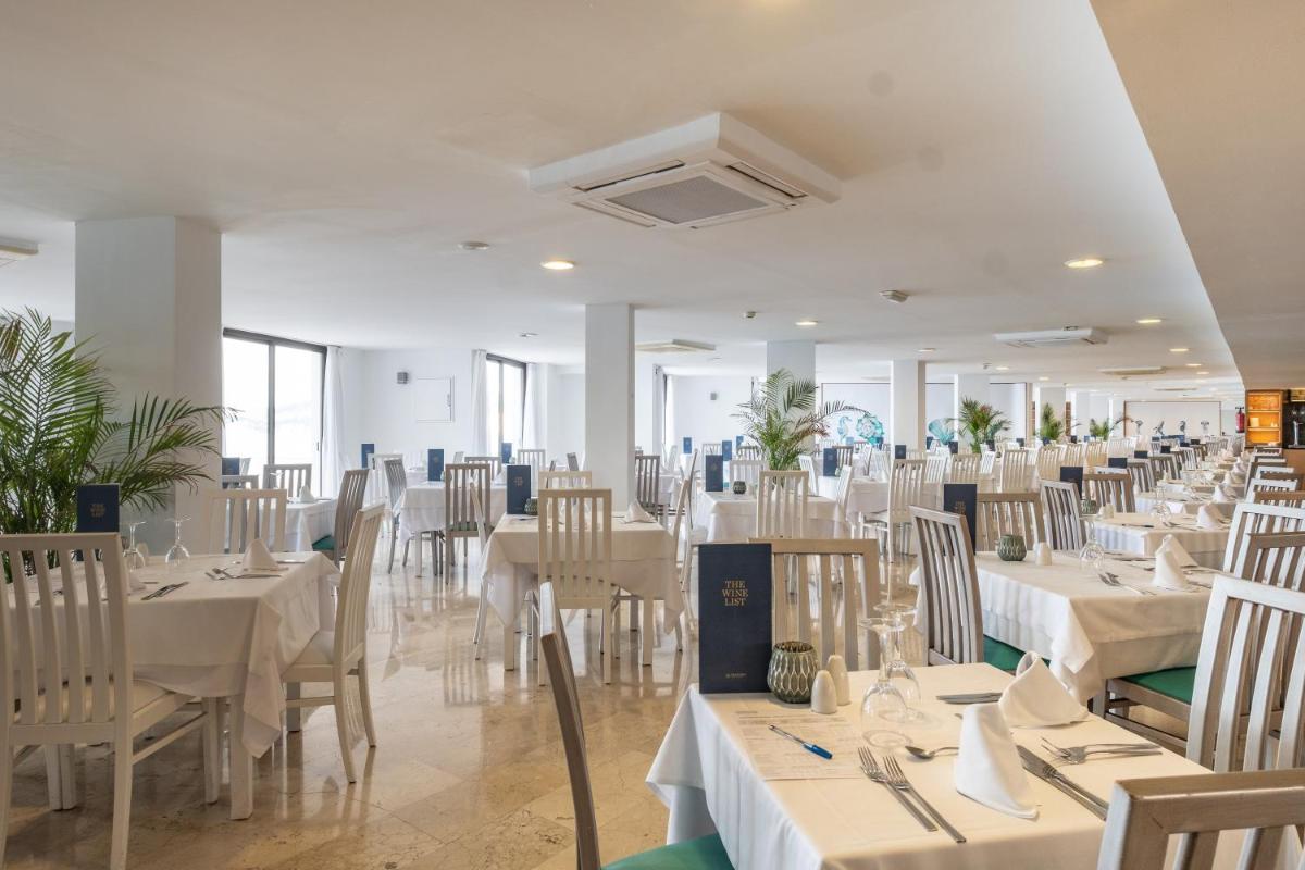 Un comedor con mesas y sillas blancas. en Sentido Fido Punta del Mar Hotel & Spa - Adults Only, en Santa Ponsa