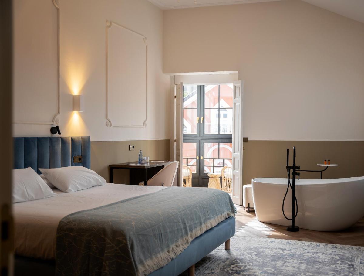 un dormitorio con una cama y una bañera en Hotel Boutique Las Indianas, en Nueva de Llanes