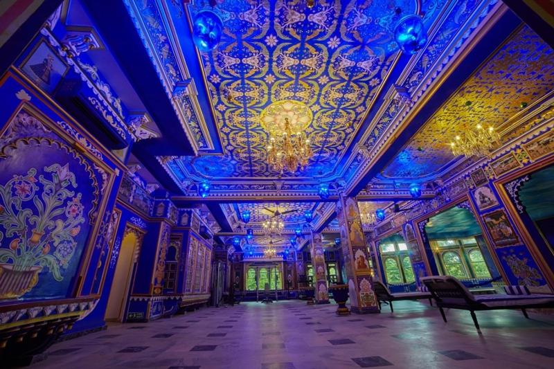 a large room with a blue ceiling and a chandelier at Chunda Palace in Udaipur