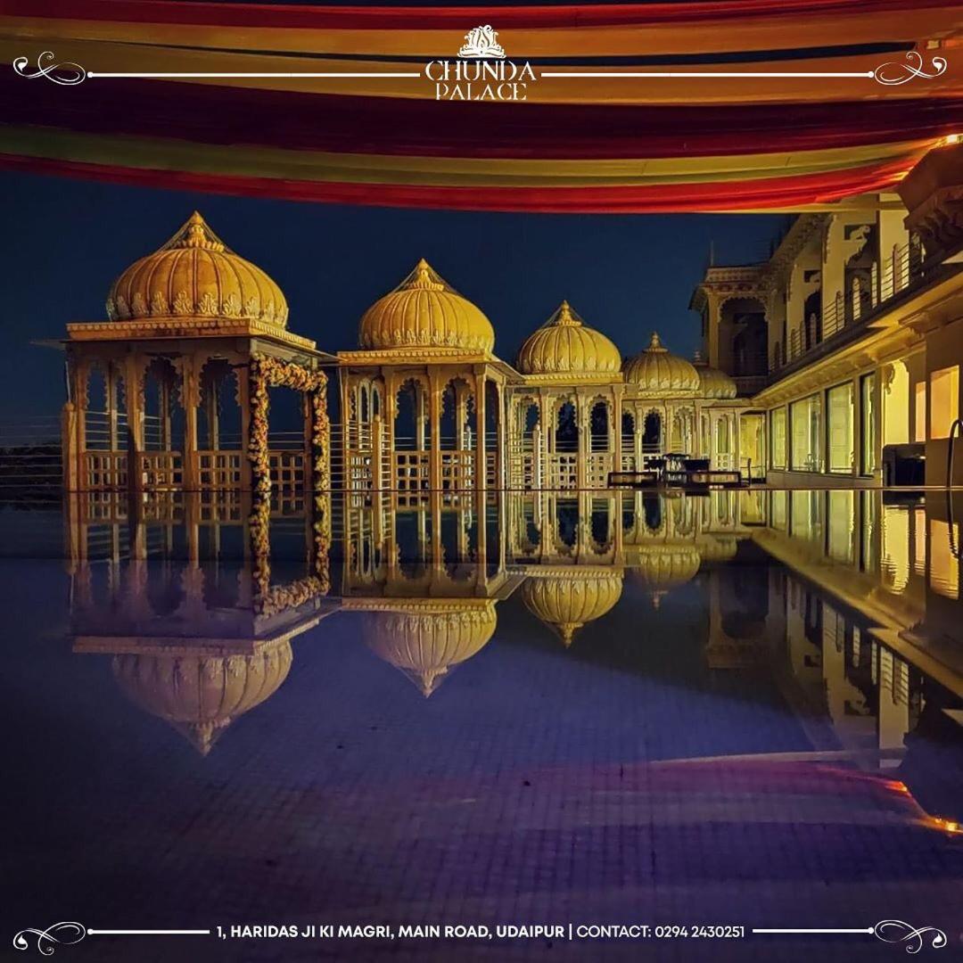 a large building with its reflection in the water at night at Chunda Palace in Udaipur