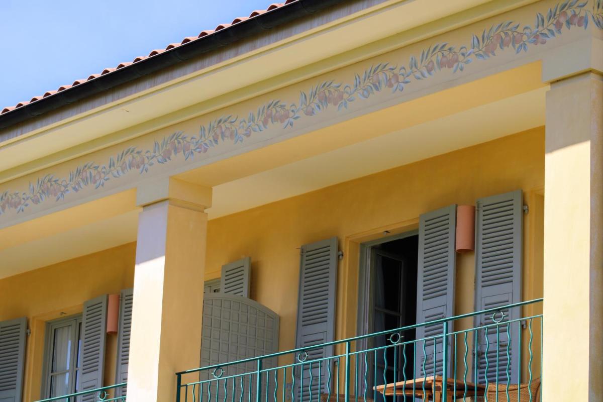Cette maison jaune dispose de volets bleus et d'un balcon. dans l'établissement Hotel Royal-Riviera, à Saint-Jean-Cap-Ferrat
